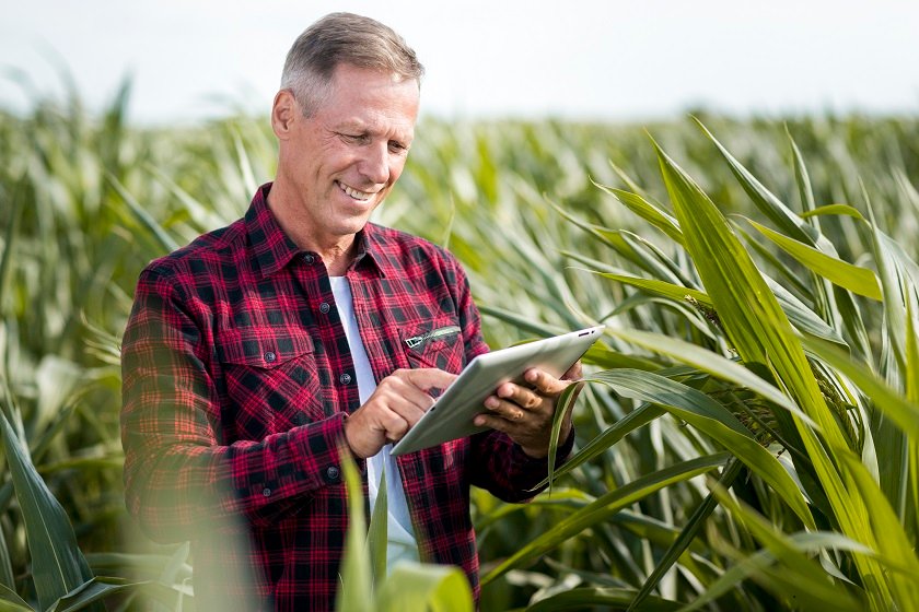 inovação no agro em imagem de um homem no campo sorrindo segurando um tablet